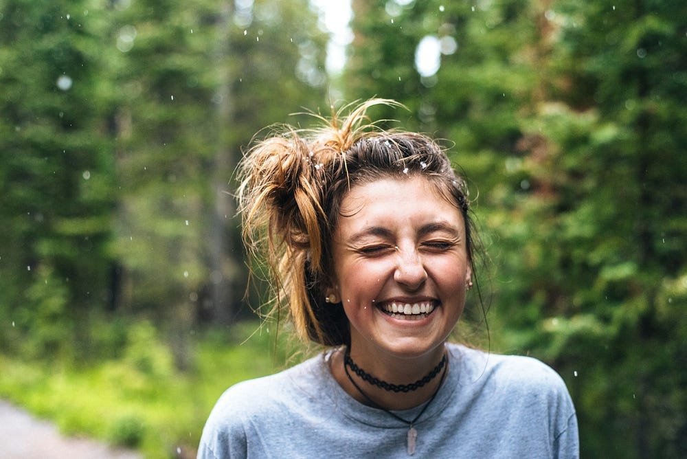 Young girl enjoying the rain outdoors and grinning or laughing with joy